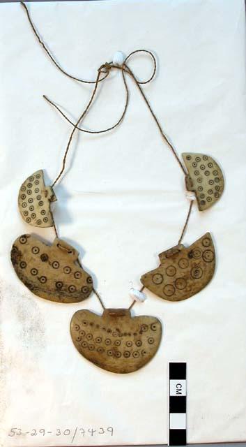 Necklace or string of pendants made of worked bone plates with incised+