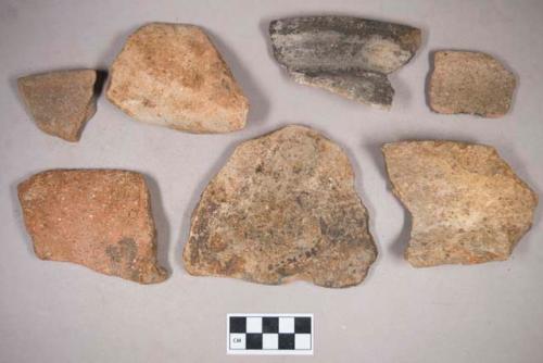 Earthenware vessel rim, body, and foot ring base sherds. Most with red painted interior and exterior. Some with white painted exterior and  interior. Some with charring. Three unaltered stones.