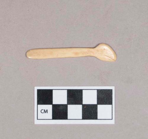 Worked animal bone object, flat, one end with possible incised face