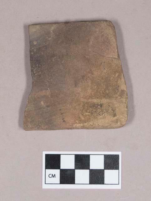 Ground stone, rectangular stone fragment, flat, two grooves on one side, possible abrading stone