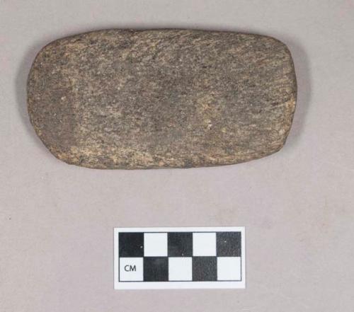 Ground stone, flat rectangular stone object, rounded edges, possible adze preform, with some red ochre on surface