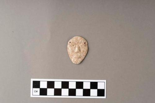 Carved stone pendant, human face