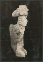 Carved stone human figure with headdress, side