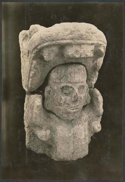 Carved stone human head in mouth of serpent