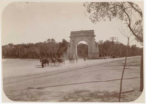 Men and burros in front of arch in park