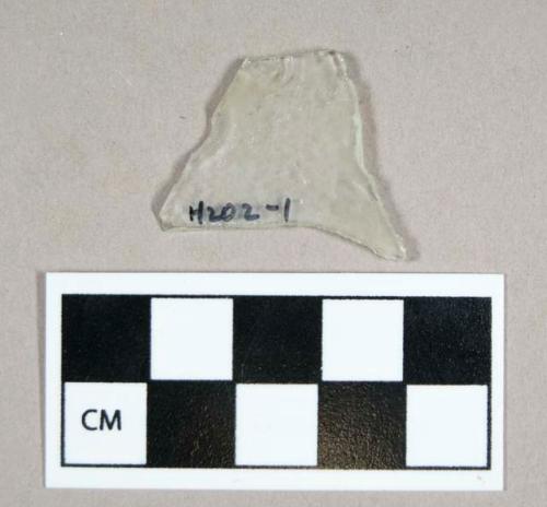 Glass, flat colorless fragment, unifacial flaking pattern, shaped into a point, missing tip