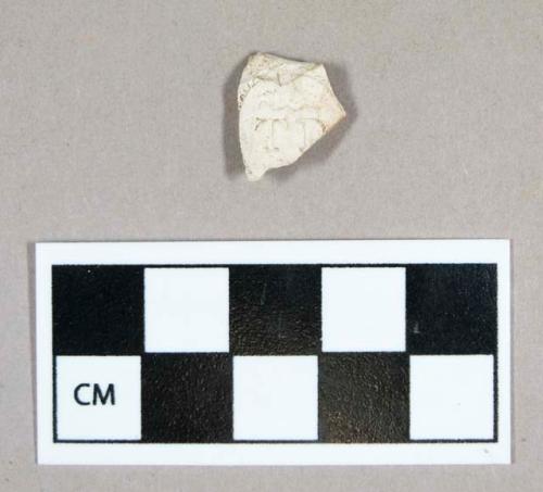 Ceramic, white clay pipe bowl fragment, molded with letters "T..." (second letter likely "D")