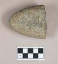 Ground stone, pecked and ground stone fragment, likely pounding stone, pitted on one side