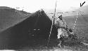 Man with pole in front of tent