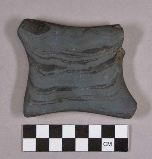 Ground stone, modified lithic object, rectangular-shaped with concave sides