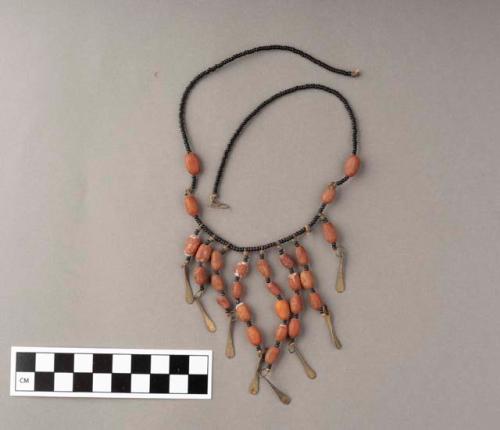 Necklace of black beads, orange/brown organic material and metal tear-drop shapes