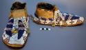 One pair of moccasins--skin with rawhide soles; forked tongue with yellow tassel