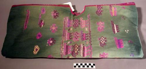 Huipil. green. green background with yellow, purple, white, and pink embroidery.