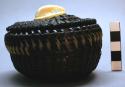 Coiled baleen basket lid; carved ivory handle represents walrus head