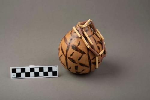 Hollow gourd with burned design, strings for hanging