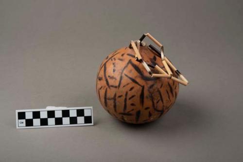 Hollow gourd with burned design, strings for hanging