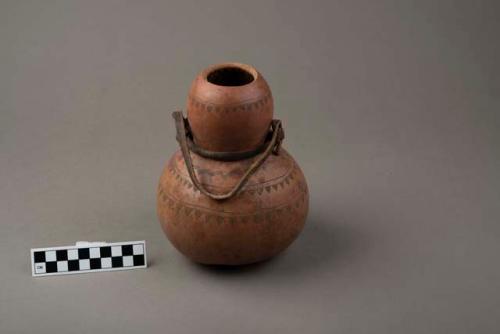 Gourd container, large, with incised design, leather strip tied around neck