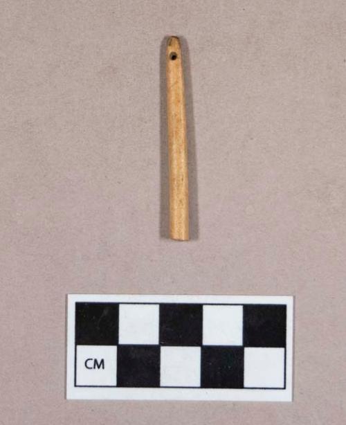 Organic, worked bone fragment, cylindrical, perforated at one end