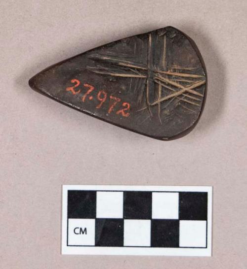 Ground stone, incised hematite object