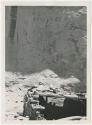 Petroglyphs of row of hand prints with ruin of structure in foreground