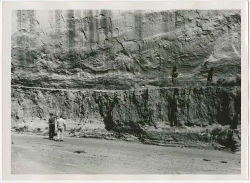 People examining rock art on cliff wall