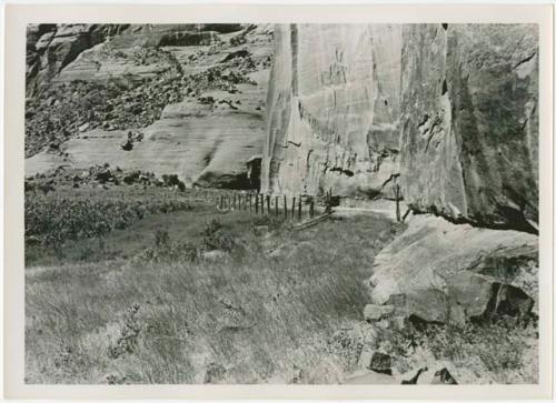 Mad-made fence at base of cliff wall