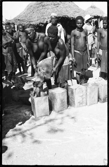 Women pouring grain from sack into tins