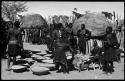 Group of people working with baskets of grain, with dogs next to them