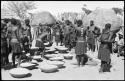 Group of people working with baskets of grain, with dogs next to them