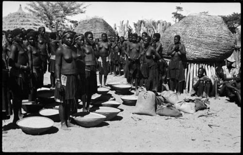 Group of people working with baskets of grain, with dogs next to them