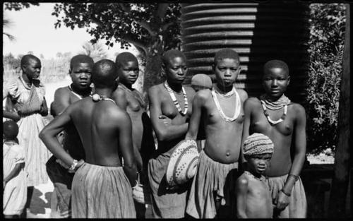 Group of women and children standing, one woman holding a basket