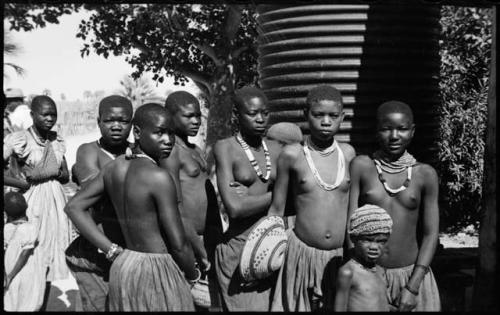 Group of women and children standing, one woman holding a basket