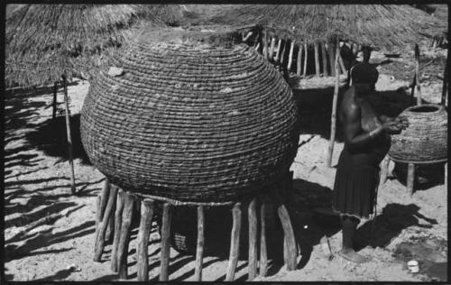 Woman standing next to a large basket on a stand