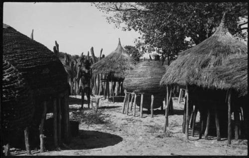 Woman standing next to storage baskets inside kraal