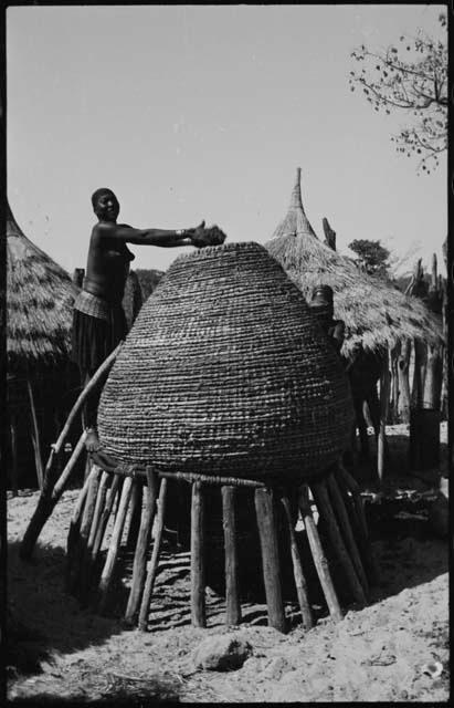 Woman standing at the top of a storage basket and putting something in it