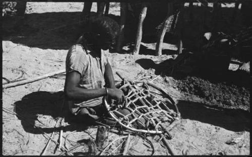 Person sitting and working, possibly mending a net