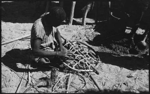 Person sitting and working, possibly mending a net