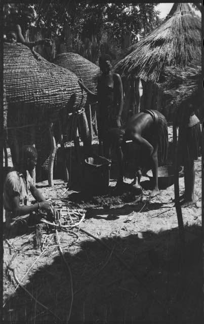 People working next to storage baskets, one possibly mending a net