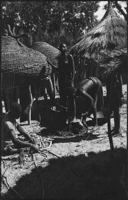 People working next to storage baskets, one possibly mending a net