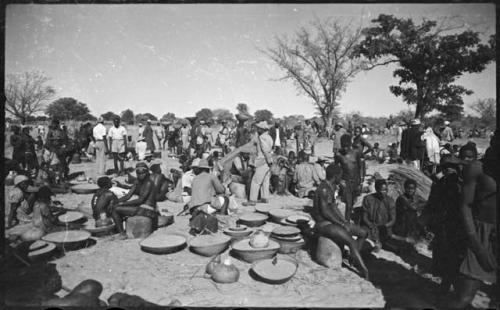 Group of people sitting and standing near baskets of grain