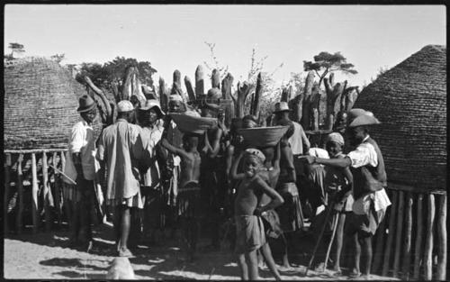 Group of people standing near storage baskets and kraal fence