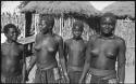 Woman and girls standing in front of huts