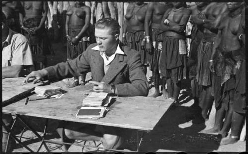 Group of people standing behind a man sitting at a table