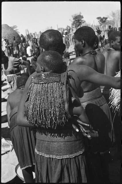 Woman carrying a child on her back in a beaded carrying bag