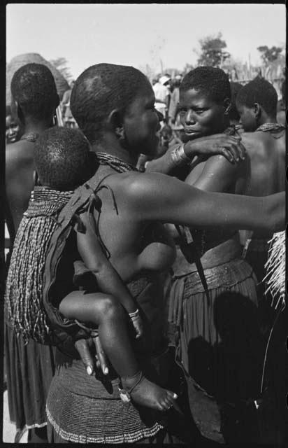 Woman carrying a child on her back in a beaded carrying bag