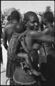 Woman carrying a child on her back in a beaded carrying bag