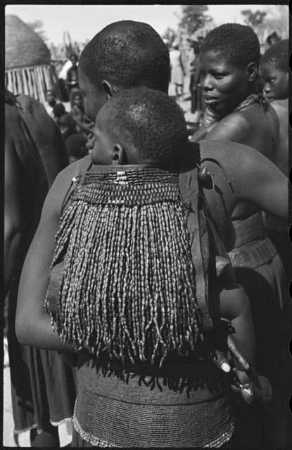 Woman carrying a child on her back in a beaded carrying bag