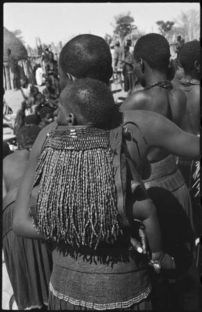 Woman carrying a child on her back in a beaded carrying bag