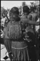 Woman carrying a child on her back in a beaded carrying bag