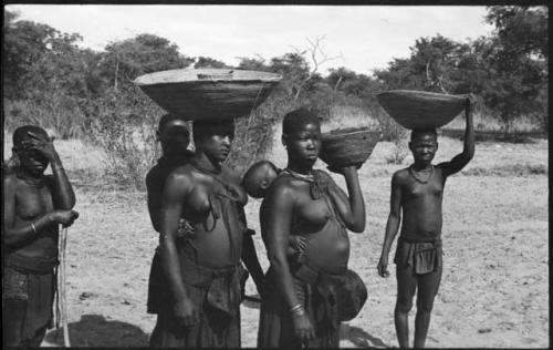 Women carrying baskets on their heads and babies on their backs